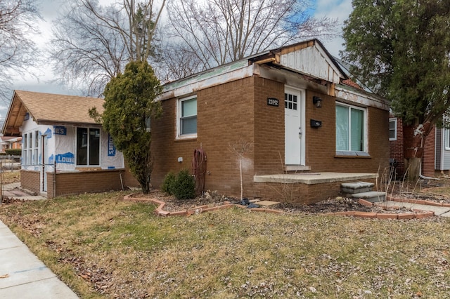 bungalow-style house featuring brick siding and a front lawn