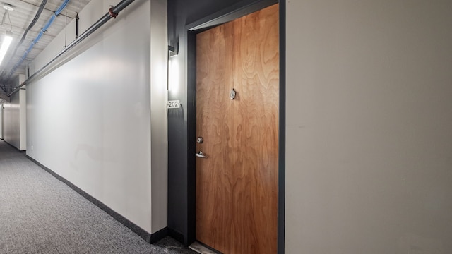 hallway featuring carpet floors and baseboards