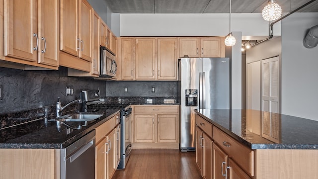 kitchen featuring tasteful backsplash, dark wood finished floors, appliances with stainless steel finishes, dark stone countertops, and a sink