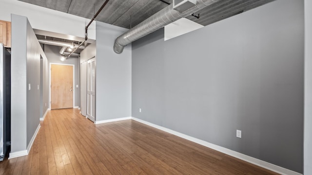 interior space with refrigerator, hardwood / wood-style floors, and baseboards