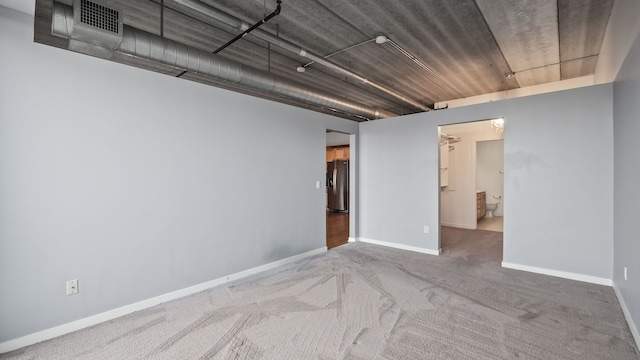 spare room with carpet floors, visible vents, and baseboards