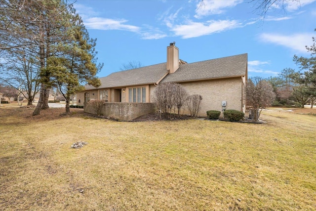 back of house featuring a lawn and a chimney