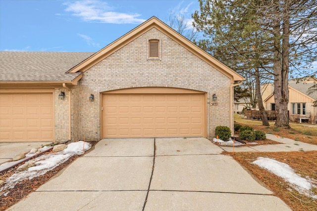 view of front of home featuring concrete driveway, brick siding, an attached garage, and a shingled roof