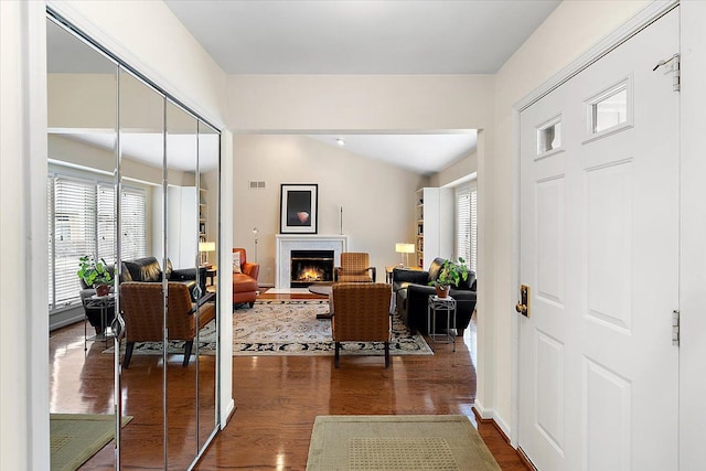 entryway featuring a fireplace with flush hearth, plenty of natural light, visible vents, and dark wood finished floors