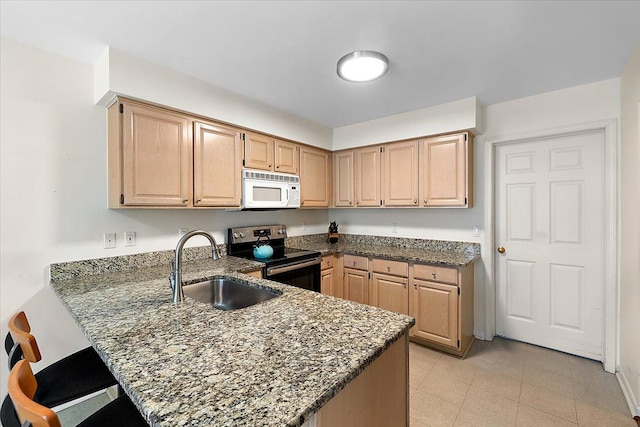 kitchen with dark stone counters, white microwave, a peninsula, stainless steel range with electric cooktop, and a sink