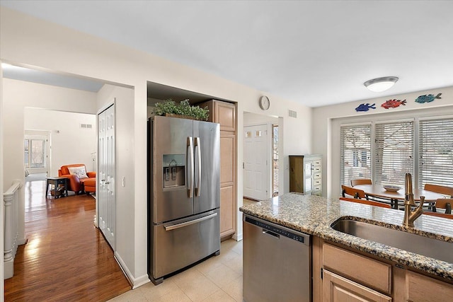 kitchen featuring a wealth of natural light, stone counters, appliances with stainless steel finishes, and a sink