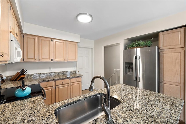 kitchen with black electric range oven, light brown cabinetry, white microwave, a sink, and stainless steel fridge