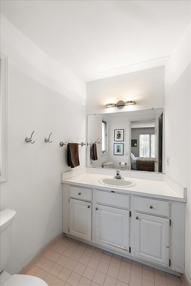 bathroom with toilet, tile patterned flooring, vanity, and ensuite bathroom