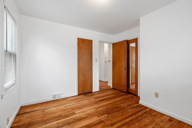 spare room featuring visible vents, baseboards, and wood finished floors