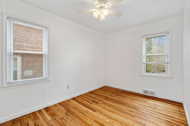 spare room featuring baseboards, ceiling fan, visible vents, and light wood-style floors