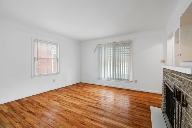 unfurnished living room with light wood finished floors, a fireplace, and baseboards