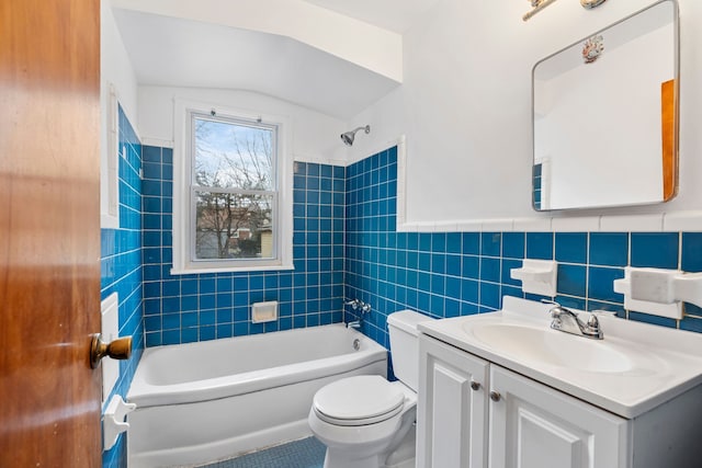 full bath with a wainscoted wall, tile walls, shower / bathtub combination, toilet, and vanity