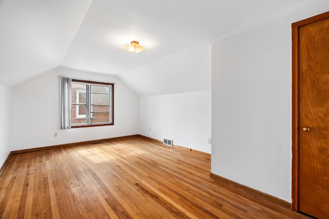 bonus room with baseboards, visible vents, vaulted ceiling, and hardwood / wood-style floors