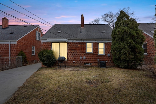 rear view of property with brick siding, a lawn, a chimney, and roof with shingles