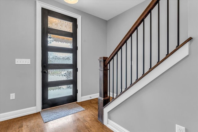 foyer entrance featuring stairs, a wealth of natural light, baseboards, and wood finished floors