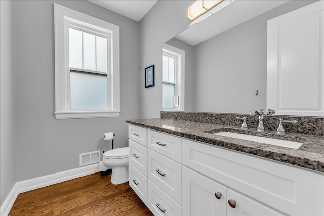 bathroom featuring toilet, plenty of natural light, wood finished floors, and visible vents