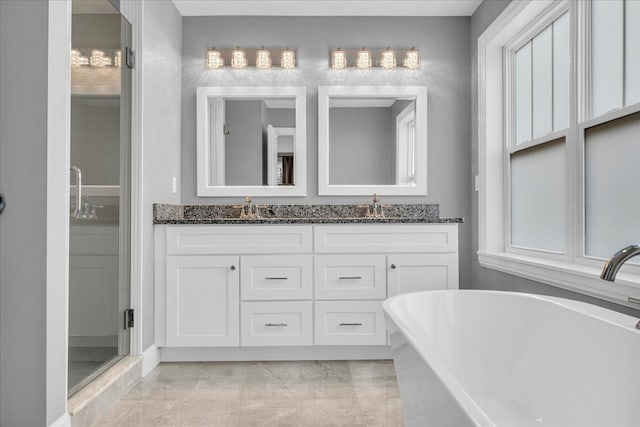 bathroom featuring double vanity, a freestanding tub, and a sink