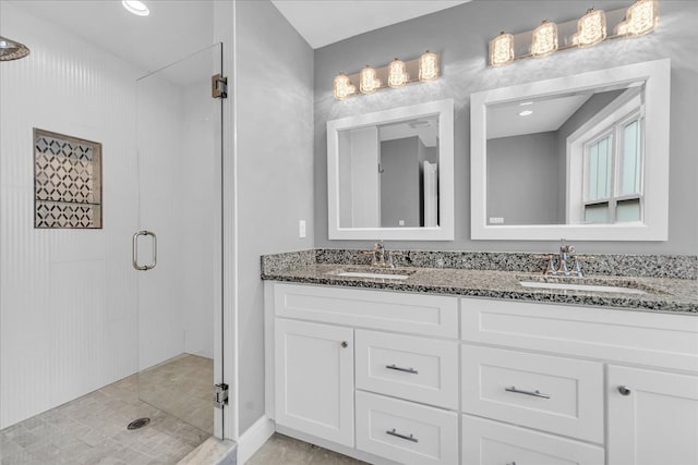 bathroom featuring double vanity, a stall shower, and a sink