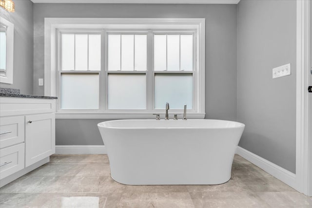 full bathroom featuring a freestanding tub, vanity, and baseboards