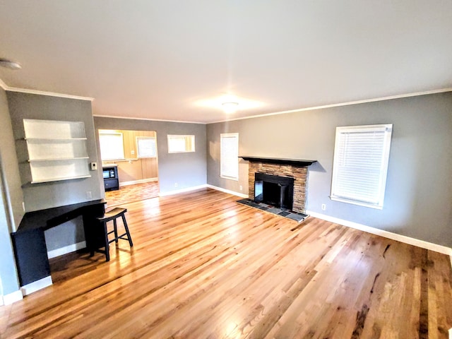 living area featuring a fireplace, baseboards, wood finished floors, and ornamental molding