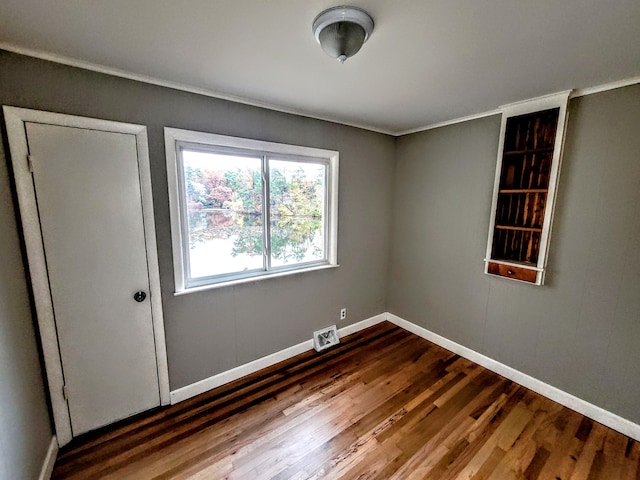 spare room with baseboards, visible vents, and dark wood-type flooring