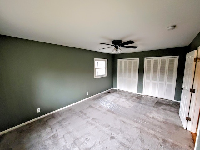 unfurnished bedroom featuring baseboards, ceiling fan, and multiple closets