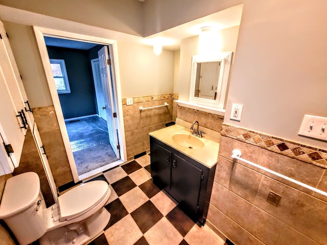 bathroom featuring a wainscoted wall, tile walls, toilet, vanity, and tile patterned floors