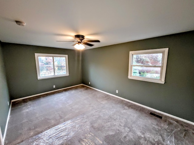 unfurnished room with baseboards, visible vents, and a ceiling fan