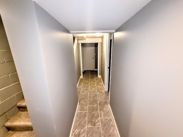 hallway featuring concrete block wall and baseboards