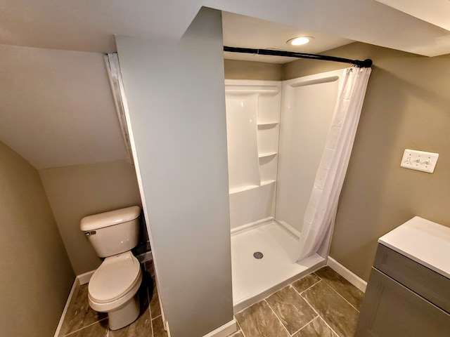 bathroom featuring toilet, a shower stall, and baseboards