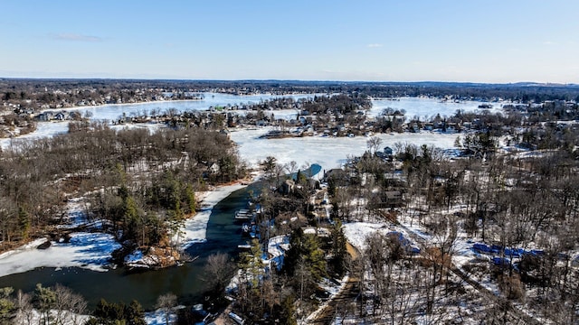 snowy aerial view with a water view and a wooded view