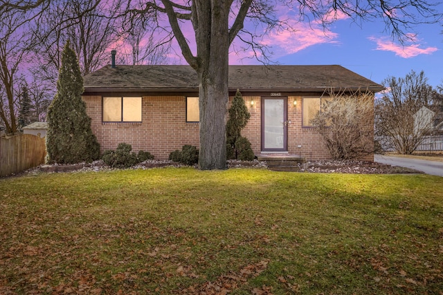 single story home featuring brick siding, a front yard, and fence