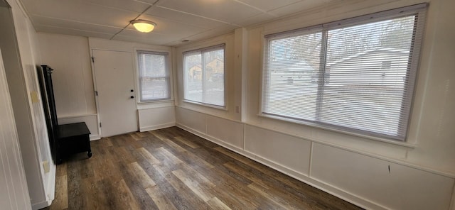 unfurnished dining area featuring dark wood-style floors and a decorative wall