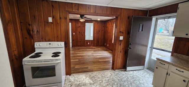 kitchen with ceiling fan, wood walls, white cabinets, white range with electric stovetop, and light floors