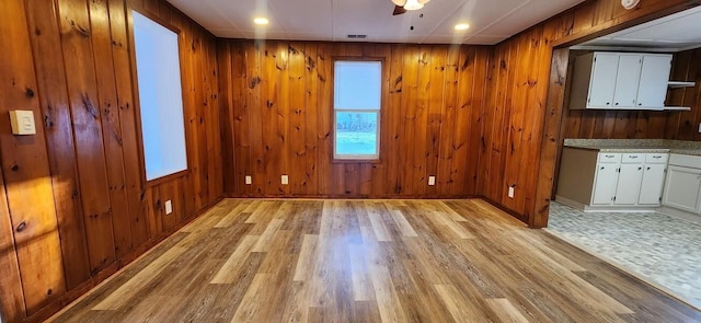 unfurnished room with mail area, wood walls, and light wood-style flooring