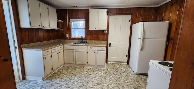 kitchen featuring white appliances, light countertops, wood walls, light floors, and a sink