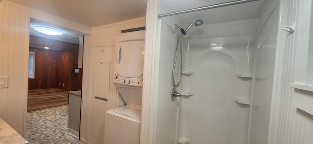 bathroom with wooden walls, walk in shower, and stacked washer / drying machine