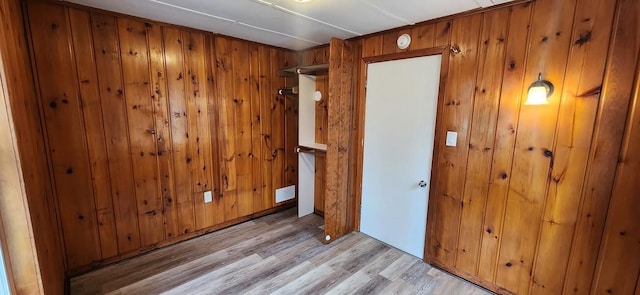 unfurnished room with light wood-type flooring, wood walls, and visible vents