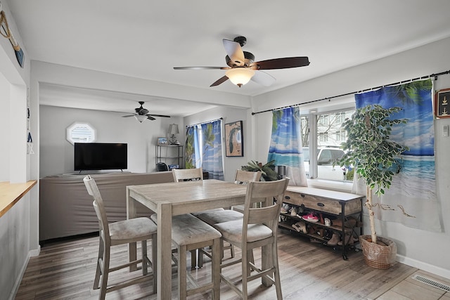 dining room with baseboards, wood finished floors, visible vents, and a healthy amount of sunlight