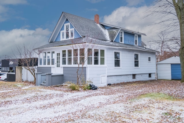 back of property with roof with shingles, a chimney, and a sunroom