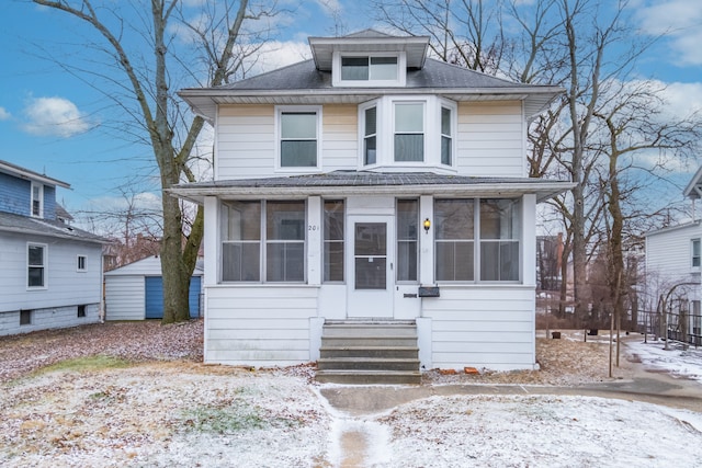 american foursquare style home featuring entry steps, a sunroom, and a shingled roof