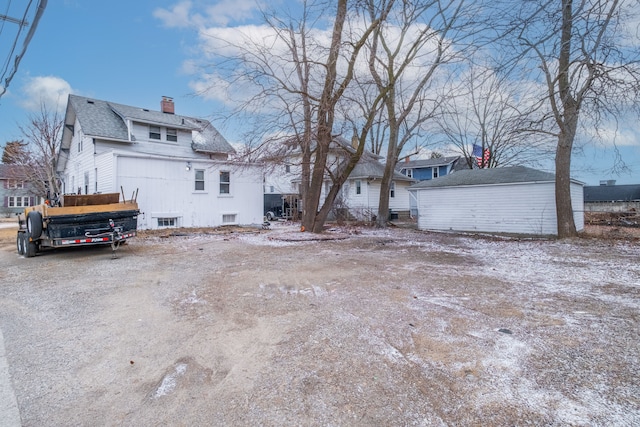 rear view of property with a chimney and a shingled roof