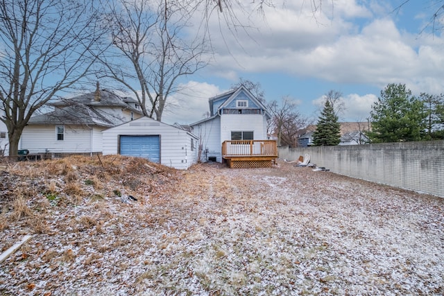 rear view of property with a garage, an outdoor structure, a deck, and fence