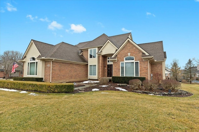 traditional-style house with a shingled roof, a front yard, and brick siding