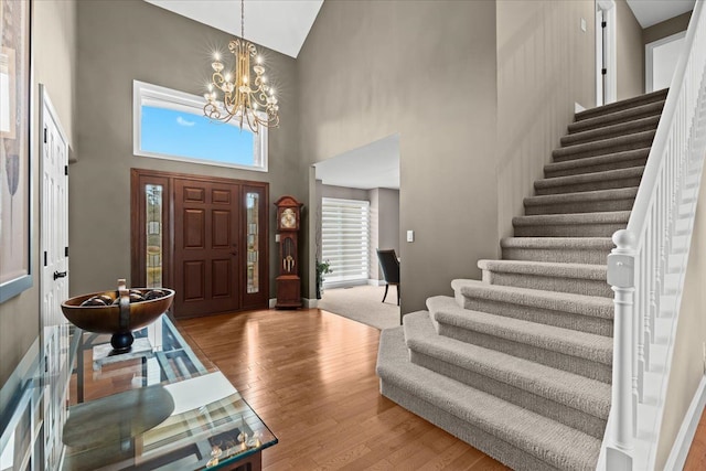 entrance foyer with stairs, a notable chandelier, and wood finished floors