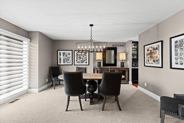 carpeted dining room with visible vents, baseboards, and a chandelier