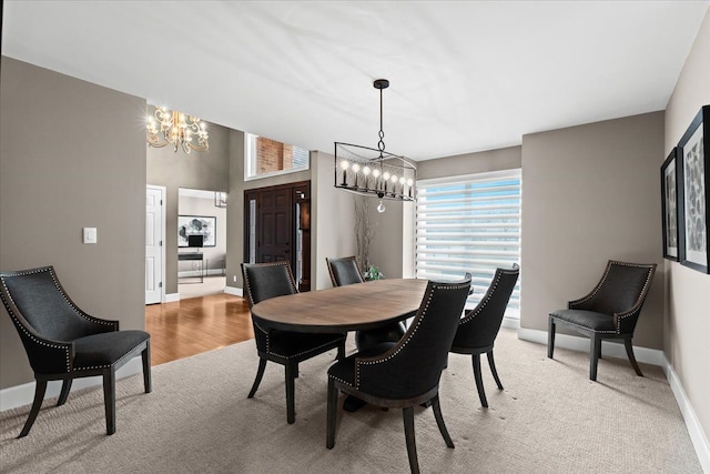 dining room with light colored carpet, a notable chandelier, and baseboards