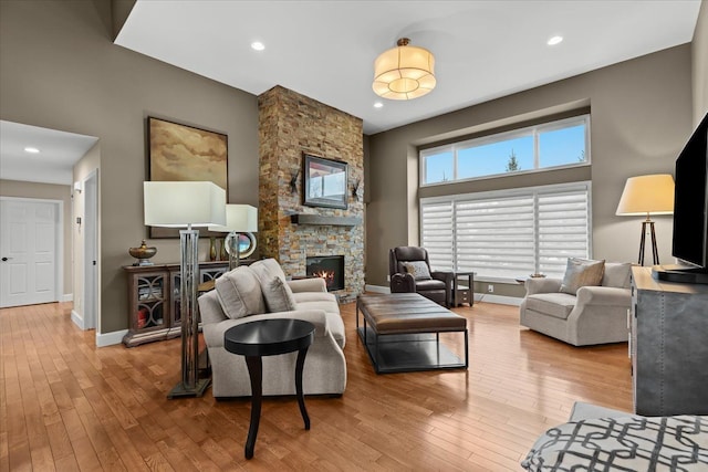 living room featuring baseboards, a towering ceiling, wood-type flooring, a fireplace, and recessed lighting