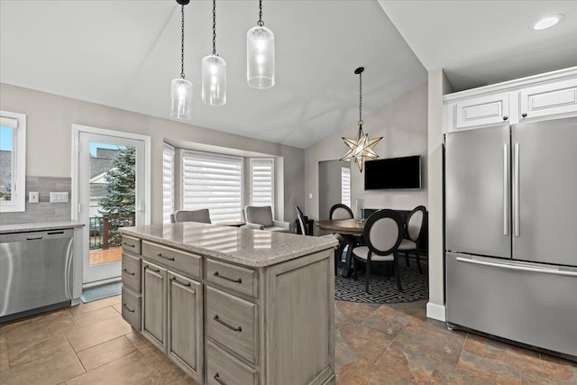 kitchen with appliances with stainless steel finishes, pendant lighting, vaulted ceiling, and backsplash