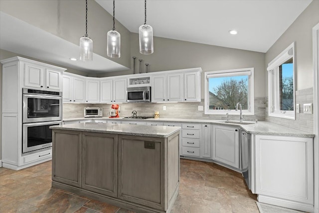 kitchen featuring stainless steel appliances, a sink, white cabinetry, and a center island